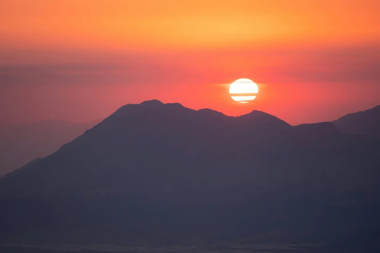 a sunset is seen behind a mountain range