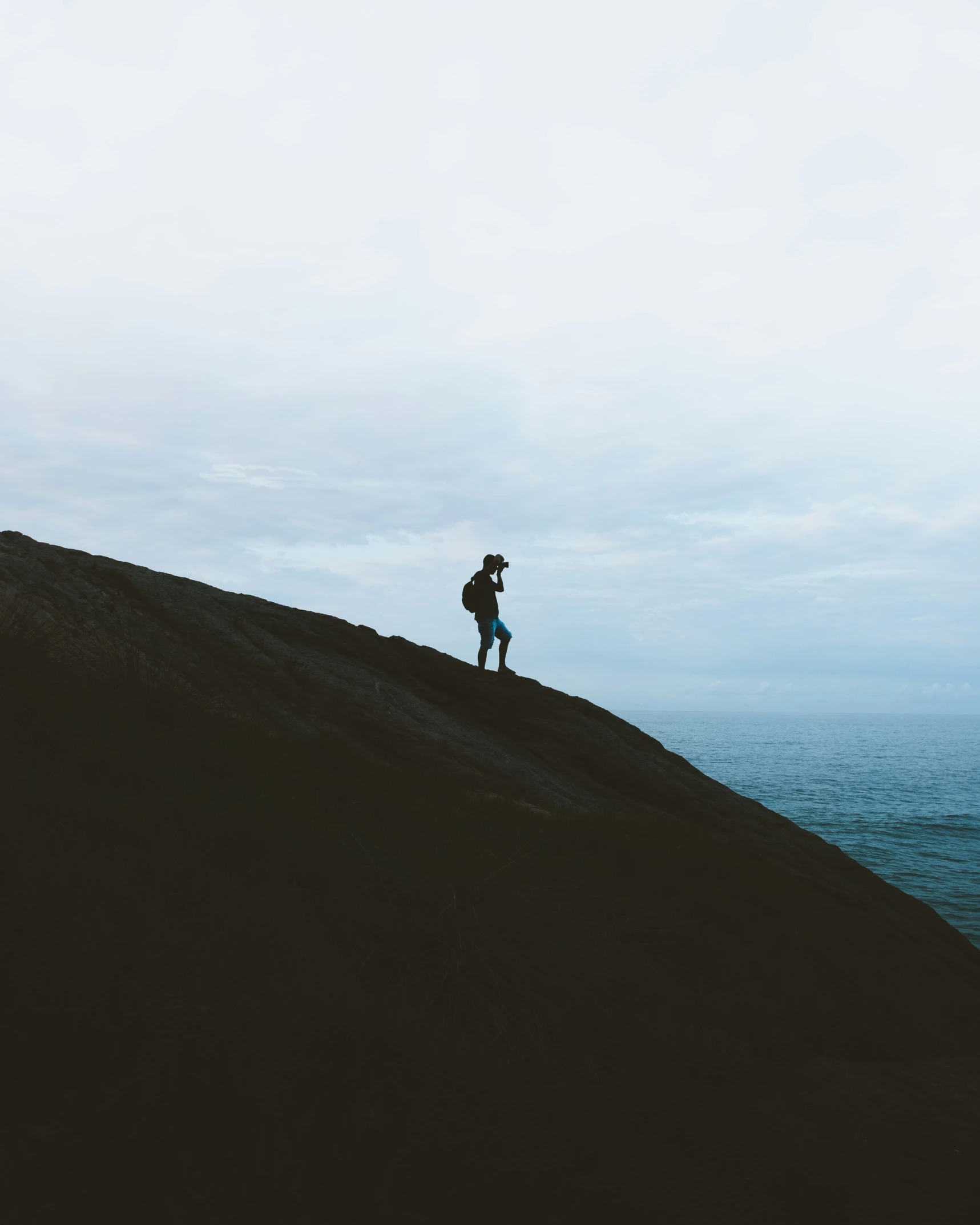 a person standing on top of a hill by the ocean