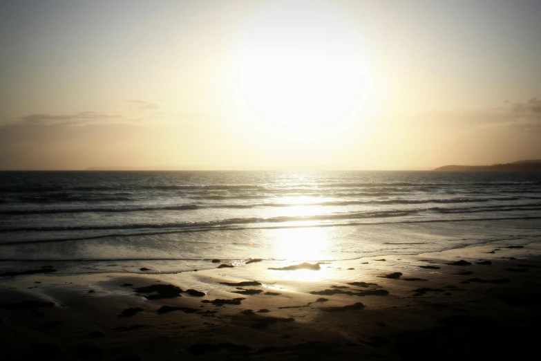 a person walking on the beach while sun is setting