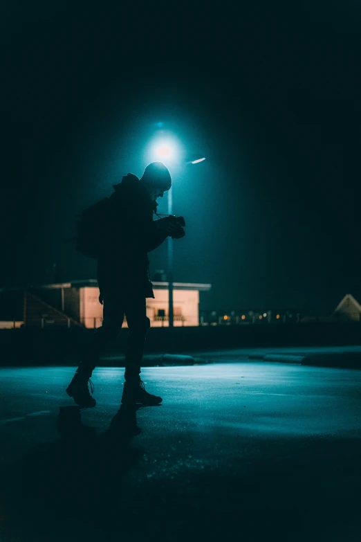 a man holding onto a backpack is walking under a street light