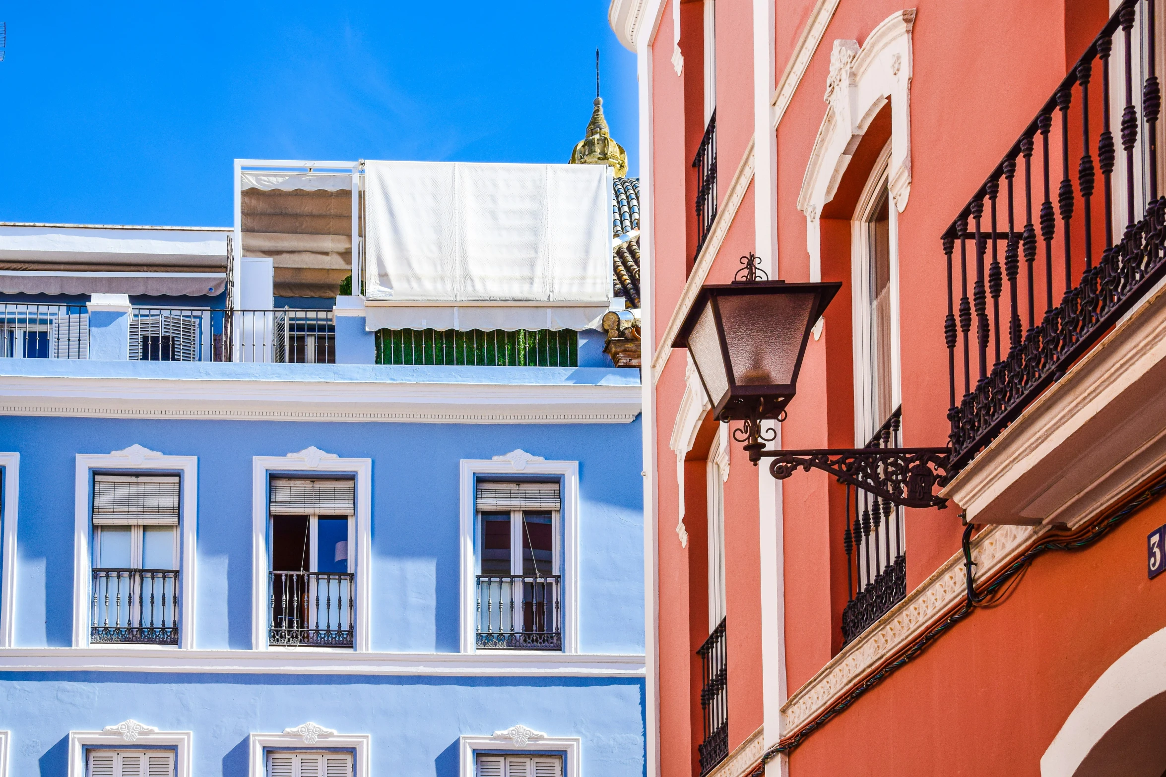 a blue building and a pink one with white windows