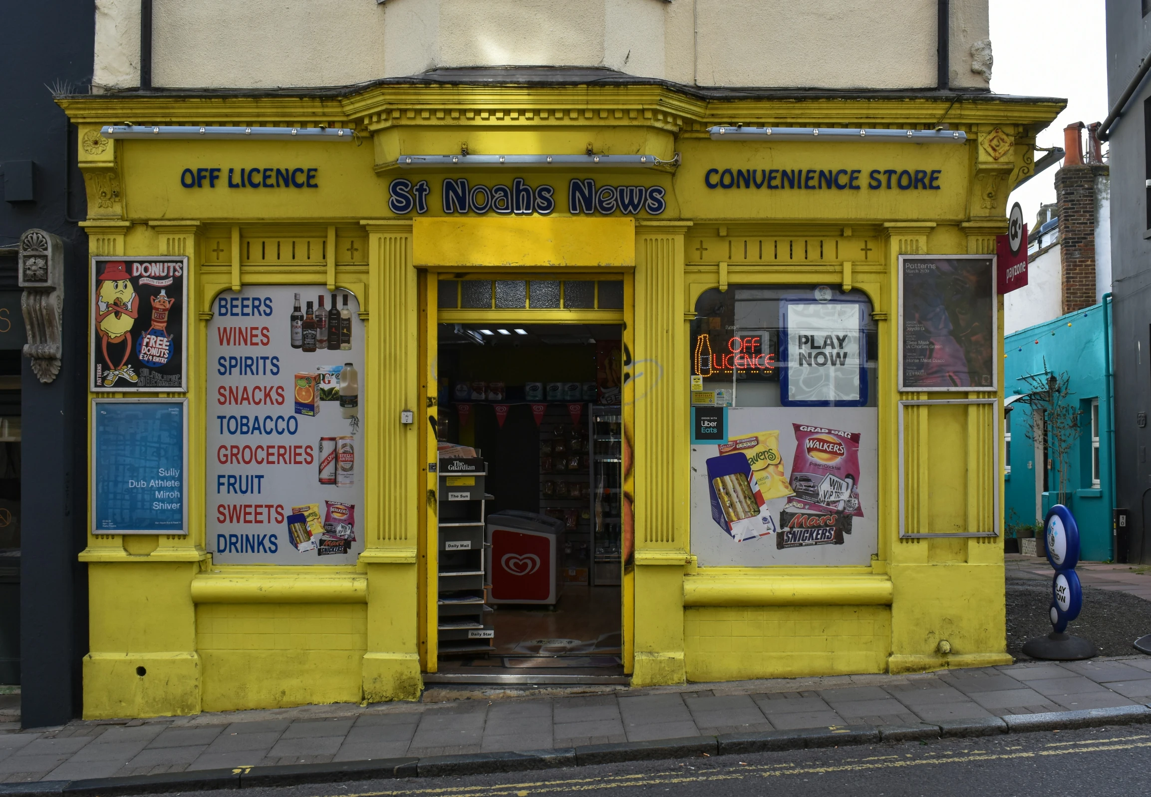 a yellow building on the street with posters in it