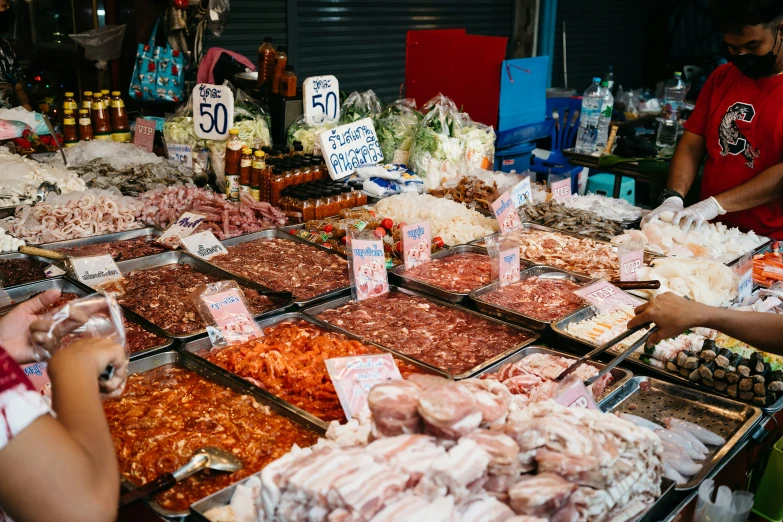 two women are standing behind a large selection of food