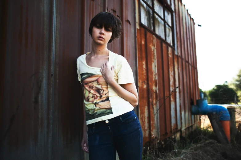 a woman leaning against a wall with a shirt on