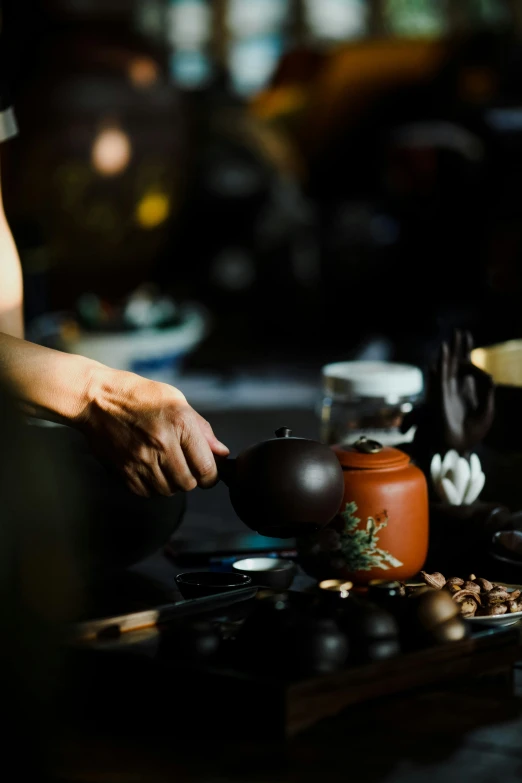 a person with tea pots in front of a table with food