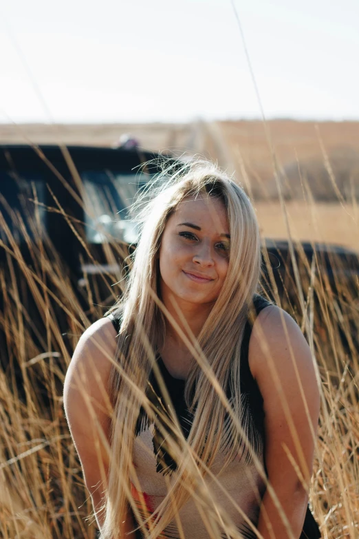 a girl in black tank top and brown shorts posing by her truck