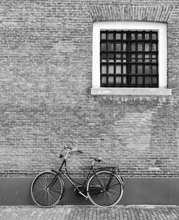 a bicycle leans against the brick wall of an empty building