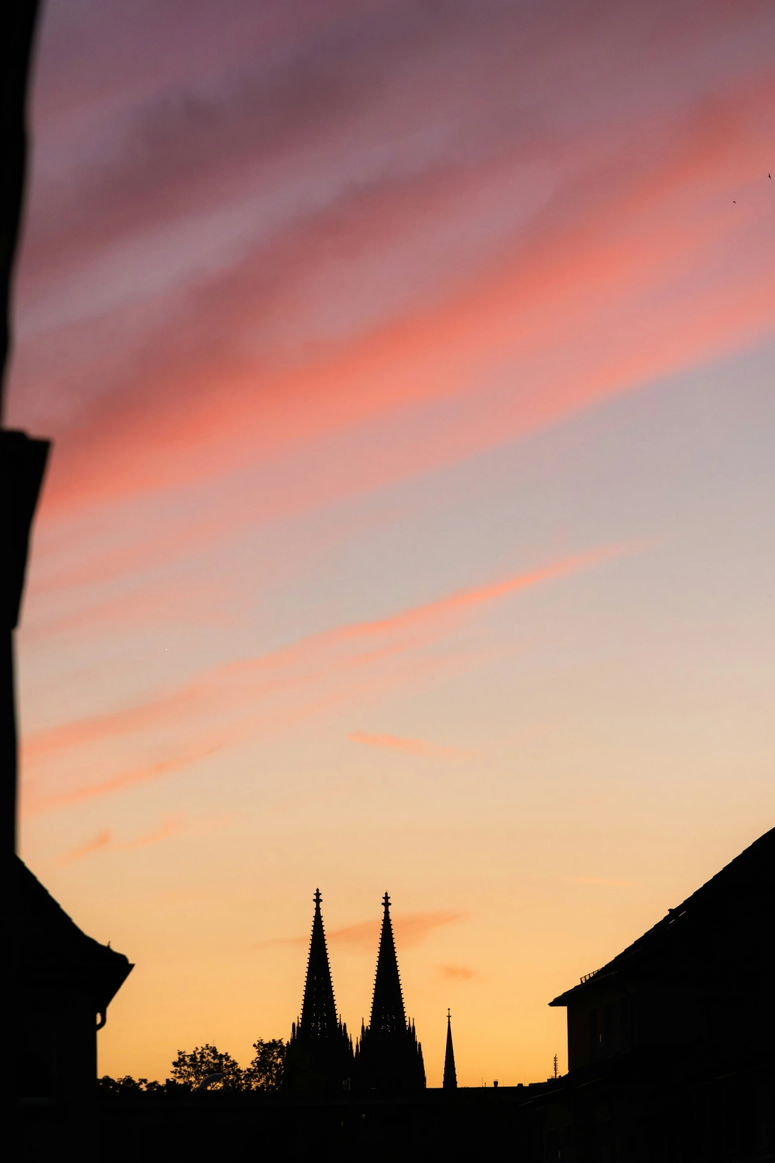 the sun setting over a church steeple with red and orange clouds