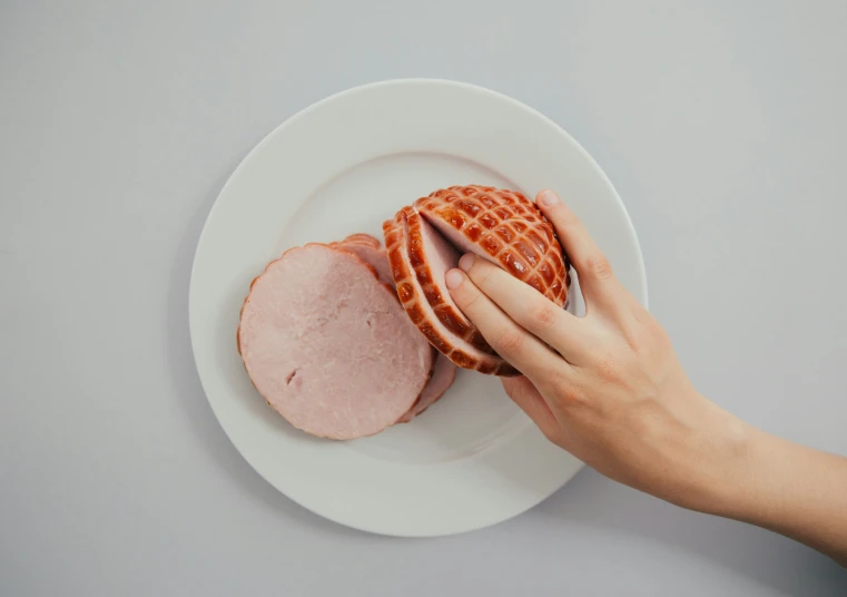 a person is holding up a turkey ham that has been cut in half