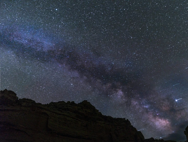 a view of the night sky with stars above the mountains