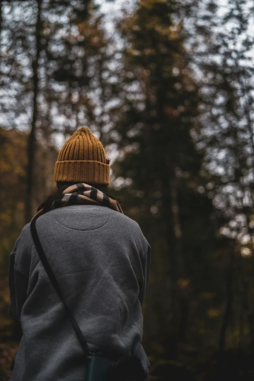 a person in a park wearing a beanie in front of trees