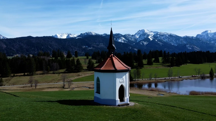 a church in a green field surrounded by mountains