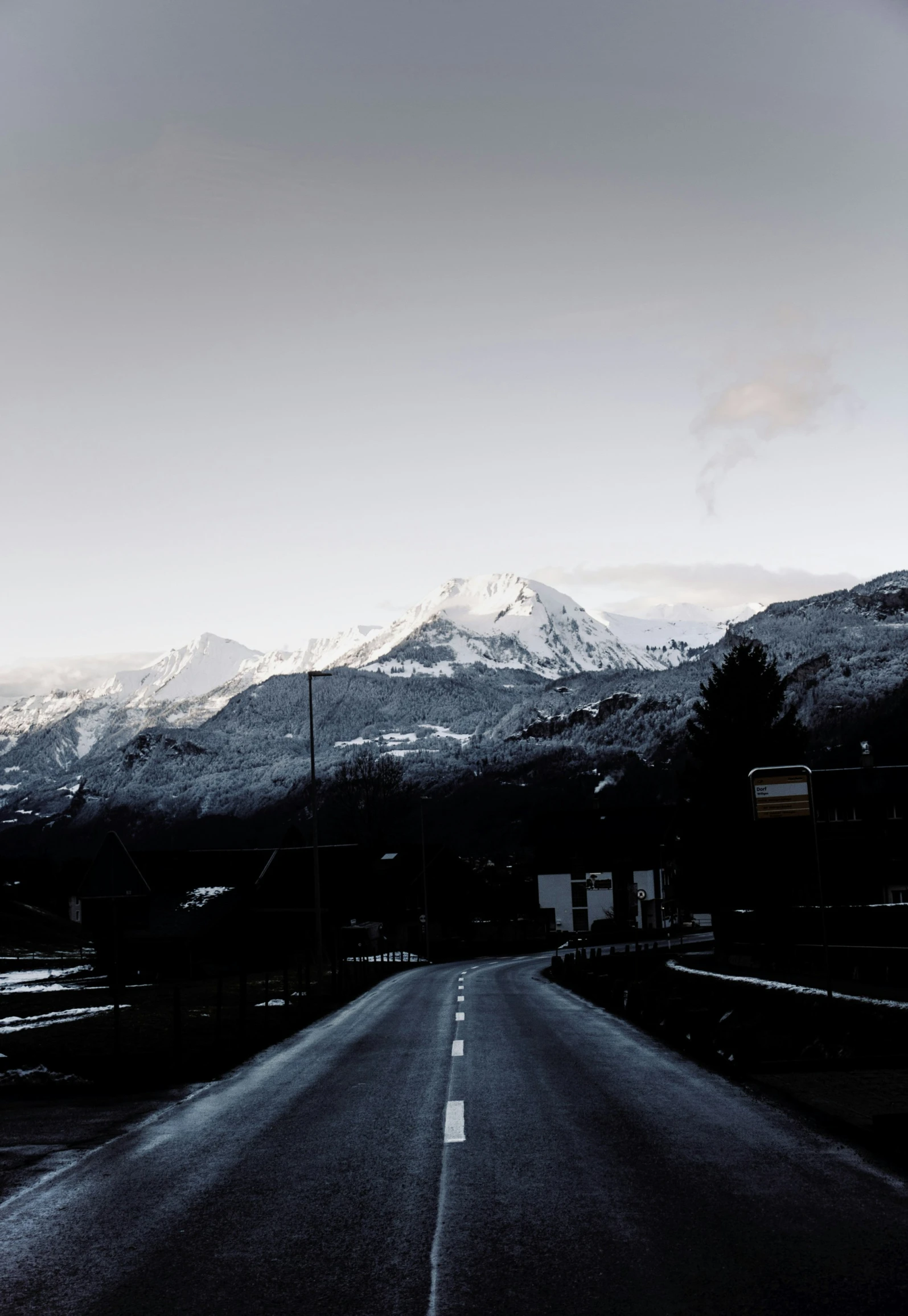 an empty highway with snowy mountains behind it