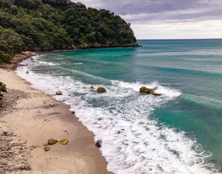 the water waves hit the sand and rocks at the shore