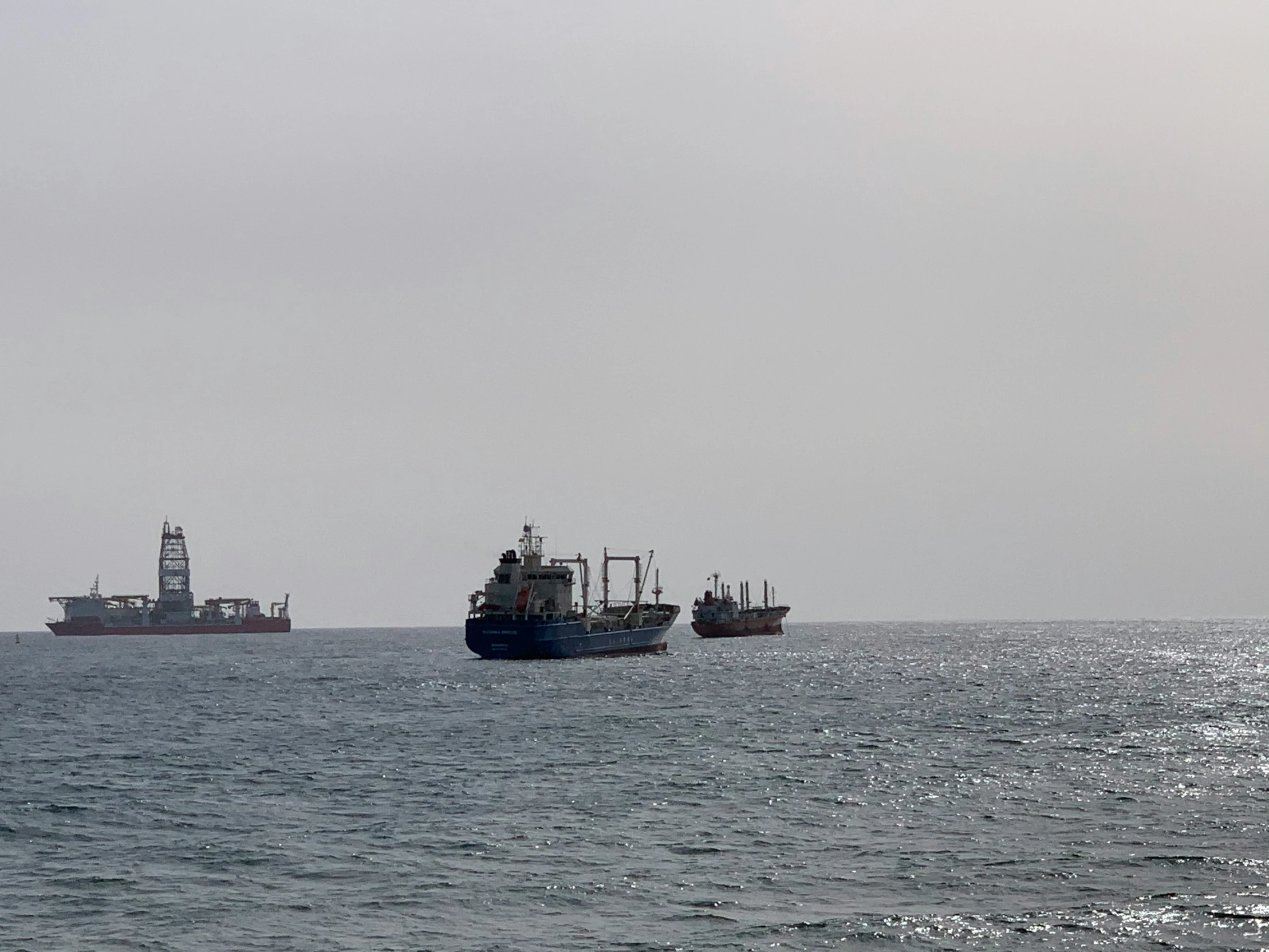 boats and cargo vessels in the ocean on a foggy day