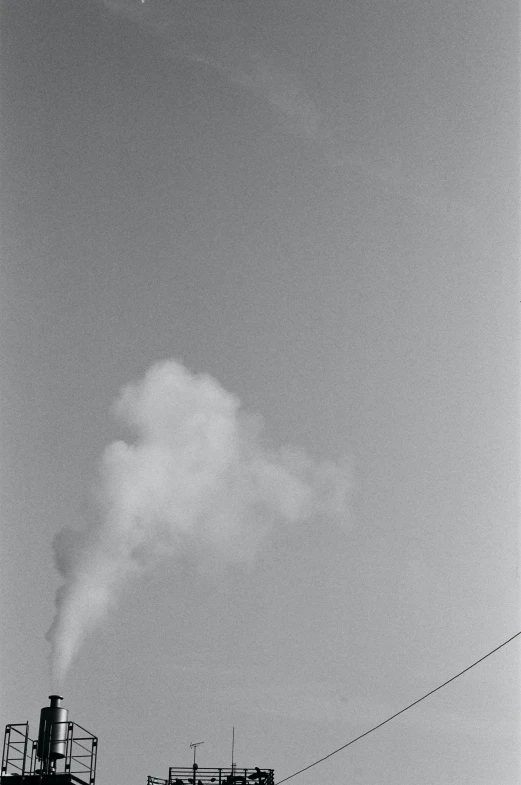 smokestacks in the air near power lines and a house