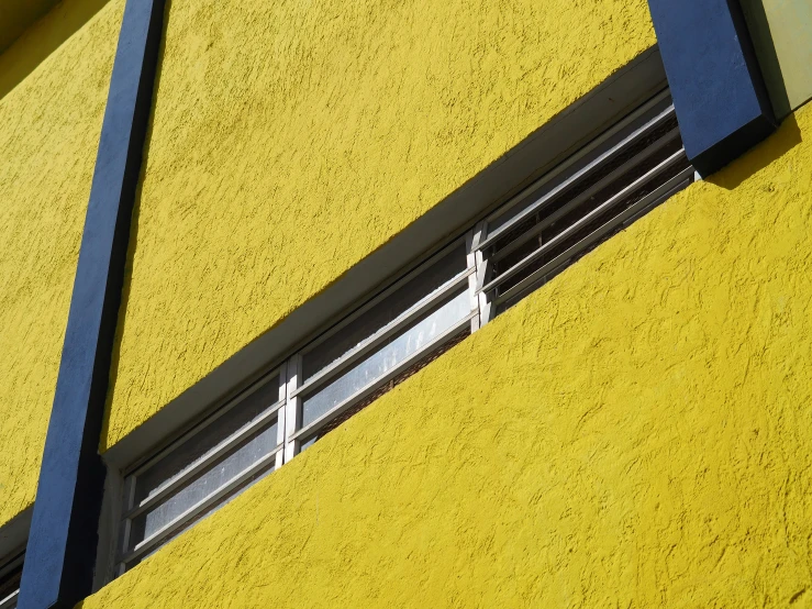 the shadow of a building's roof window shows what appears to be a yellow wall