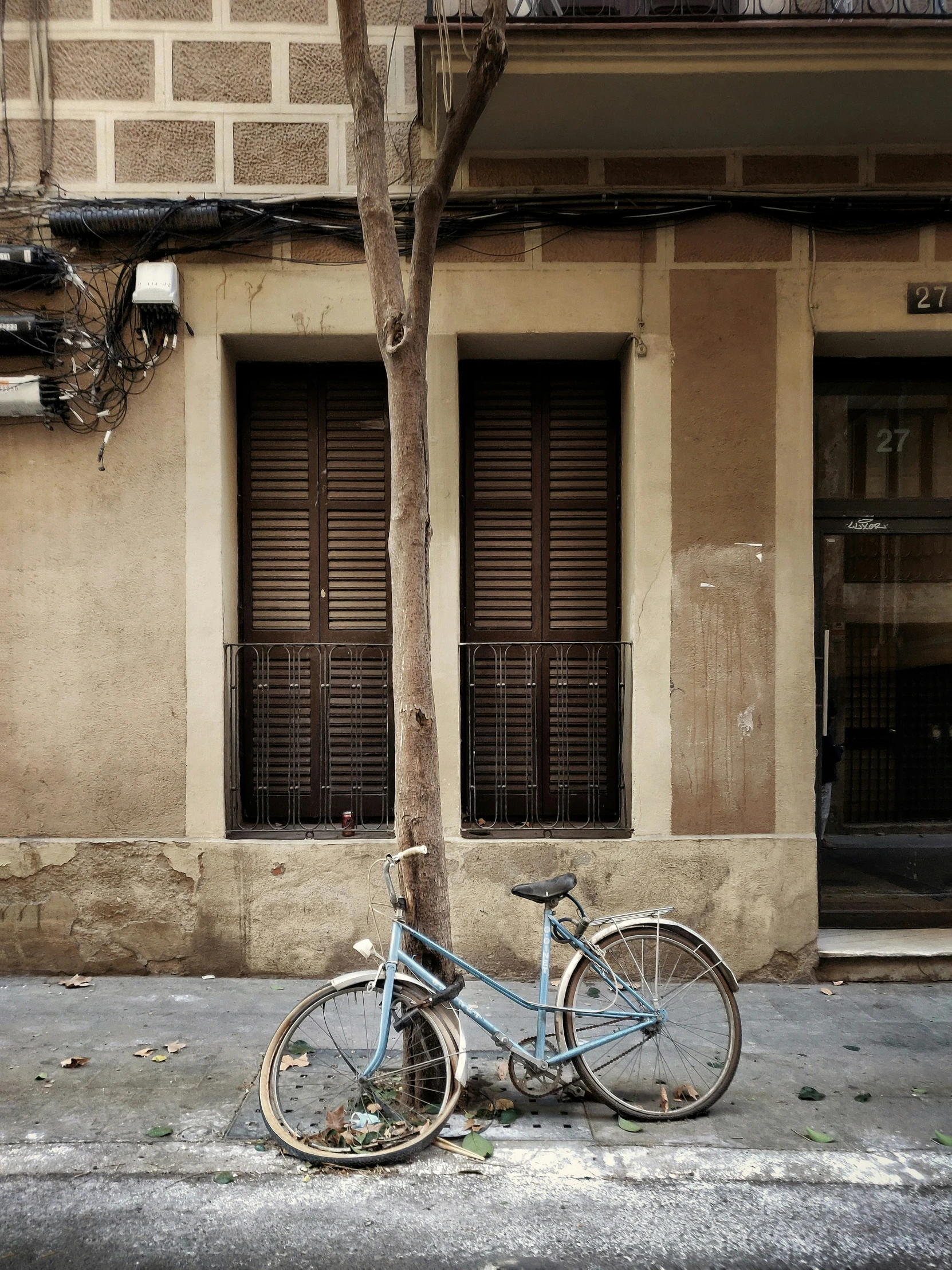 a blue bike sits next to a tree on the street