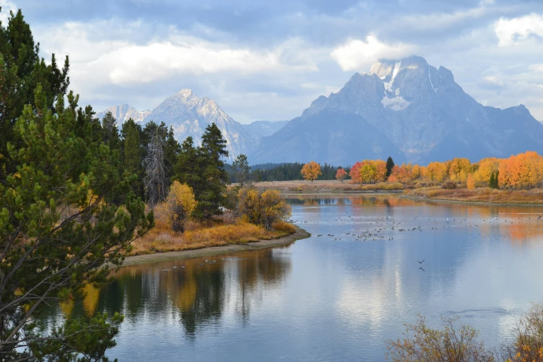 a view of mountains, trees and water in autumn