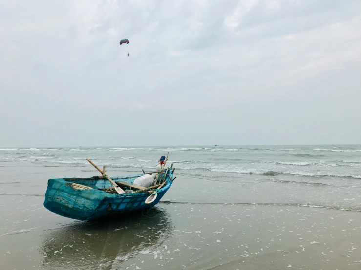 a boat sitting on the beach, waiting to be washed up