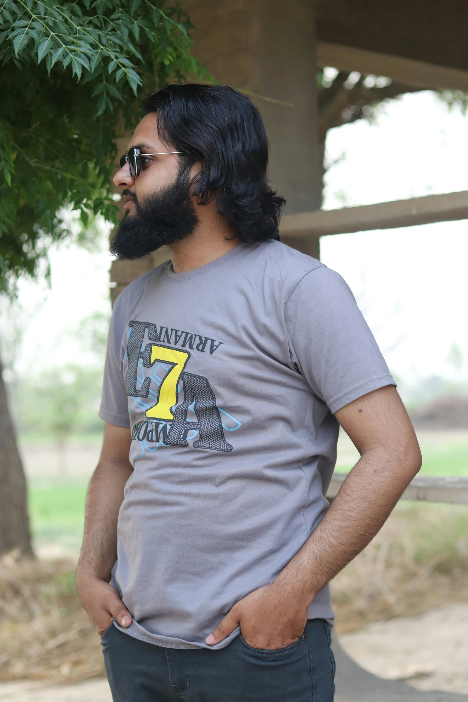 a man with long hair standing up near some trees