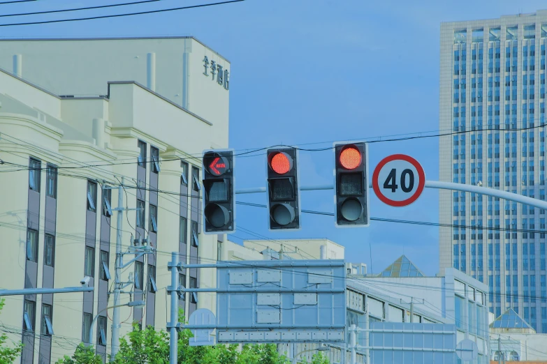 a red traffic light hanging from wires and a sign