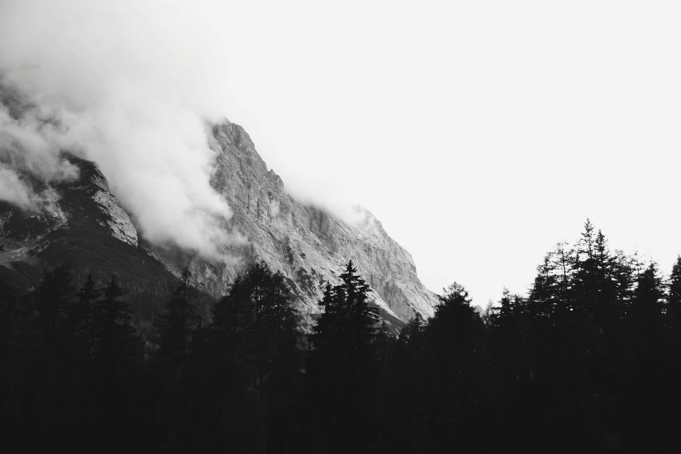 black and white po of clouds rolling over mountains