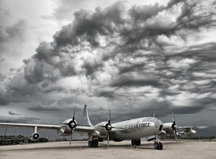 three planes parked in the sand in front of an approaching cloudy sky