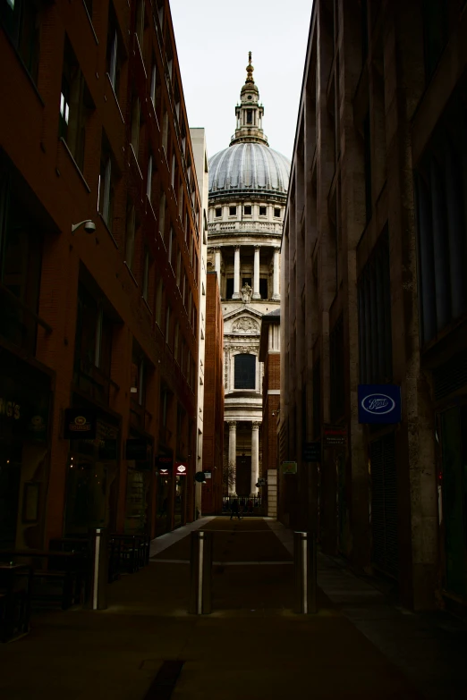 a narrow street between brick buildings with a domed building in the background