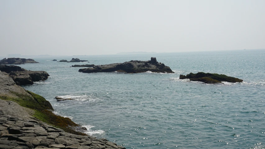 a couple of people are sitting on rocks near the water