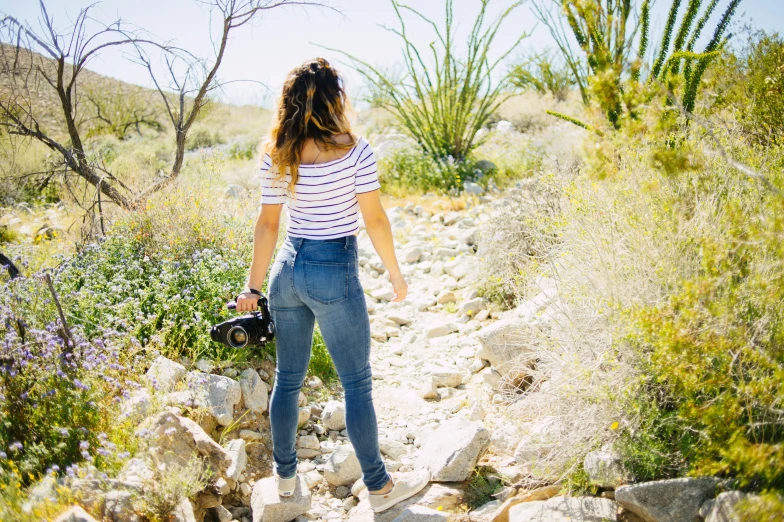 a woman is standing near rocks and bushes