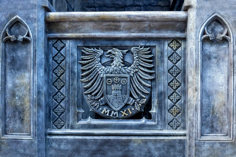 a grey ornate iron door with a crest