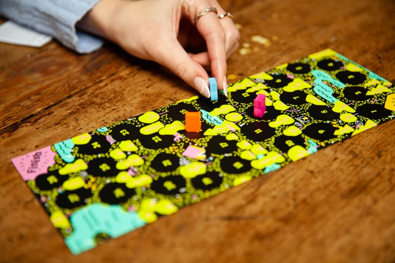 a woman's hand with pink nails is trying to do some nail art on a piece of fabric