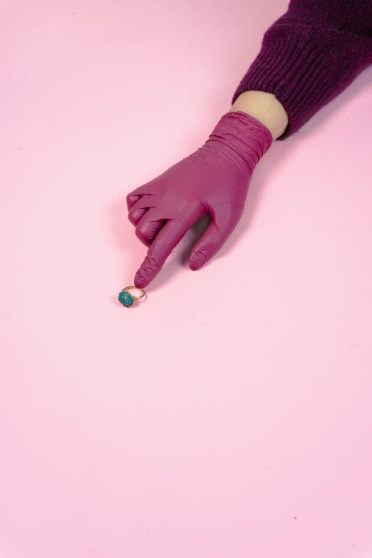 a purple glove with green on sits on a pink background