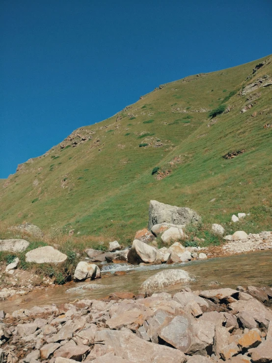 a stream running through a rocky stream surrounded by grass