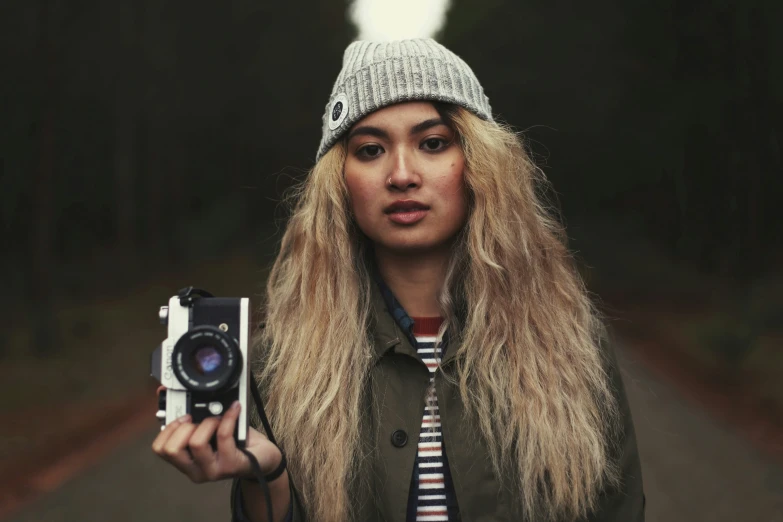 a woman holds a camera and lens in one hand