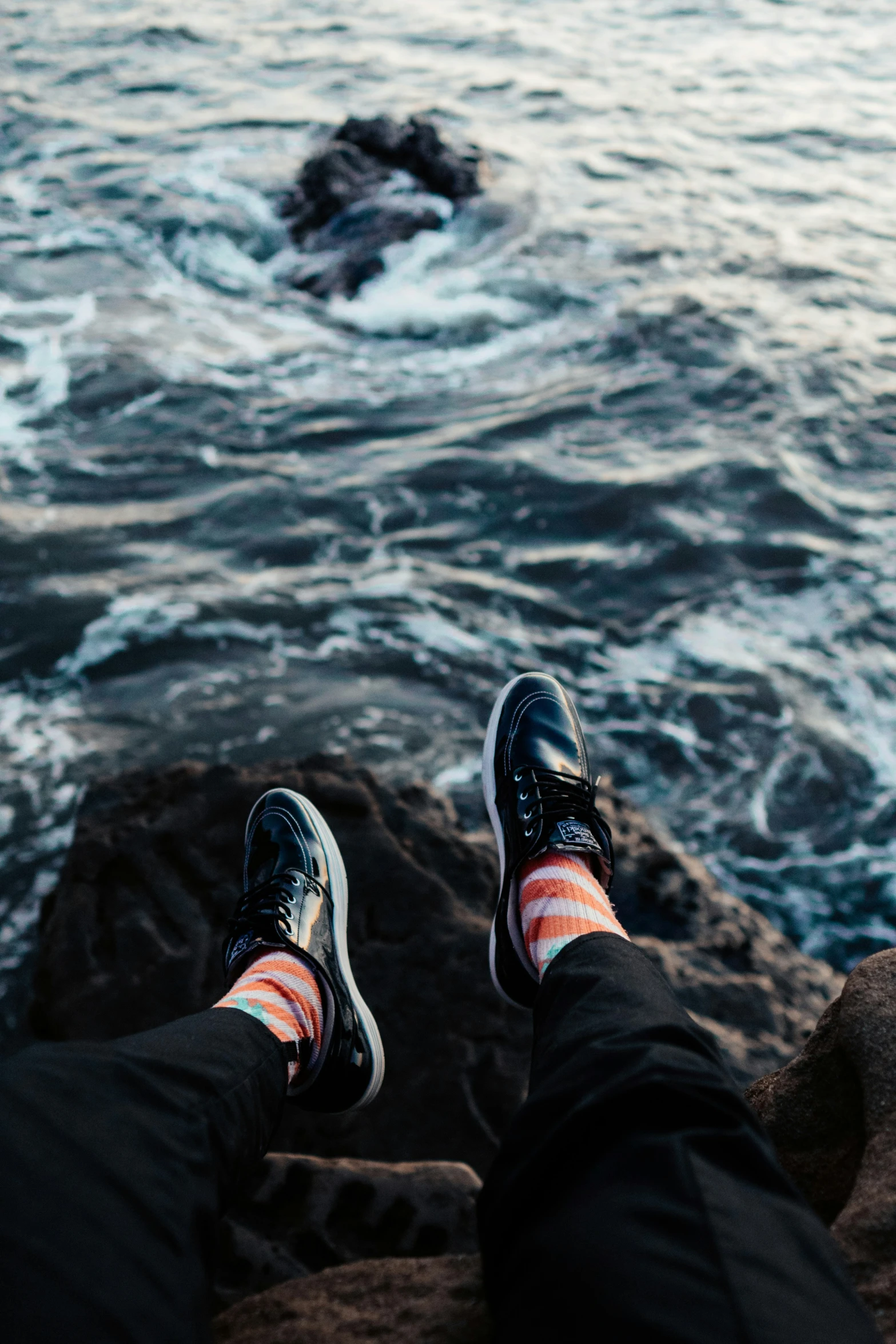 the person is sitting on the beach next to the water