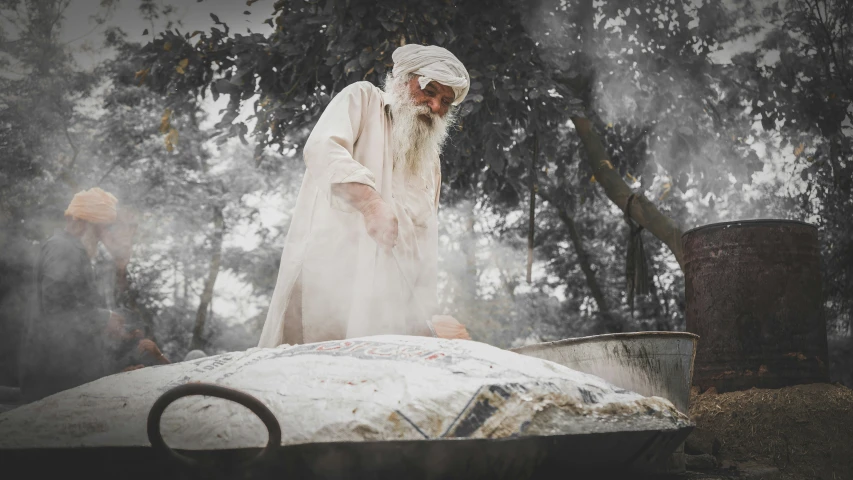 a man stands near a bed that is covered with white fabric