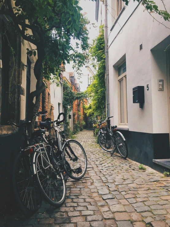 several bikes are parked up against a wall on the brick sidewalk