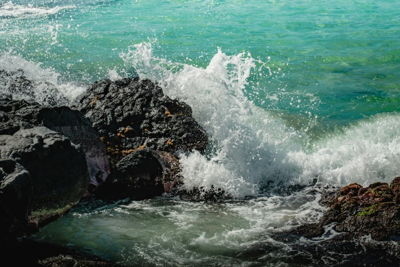 a wave crashes on a rocky outcropping by the ocean