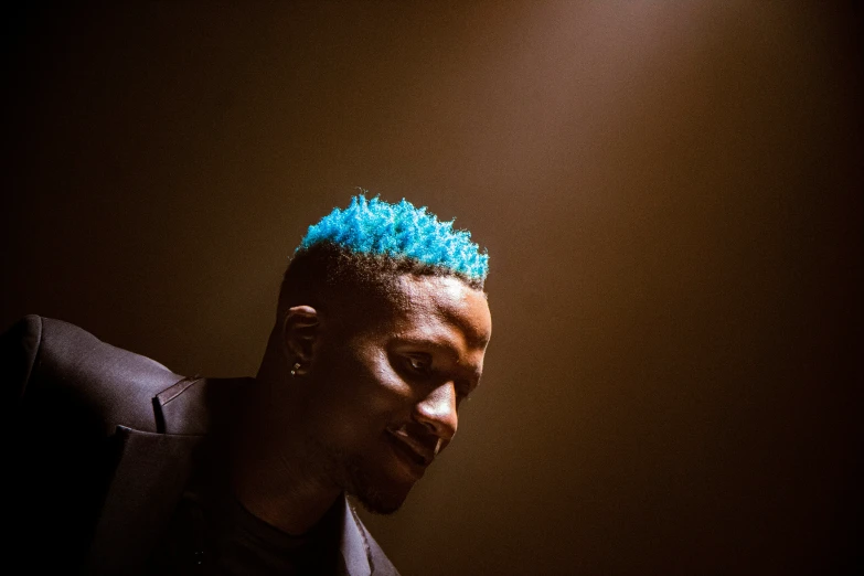 a person wearing blue hair is looking down at his cell phone