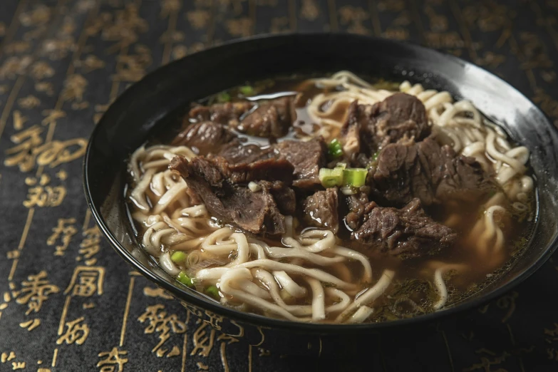 beef and noodles are served in a black bowl