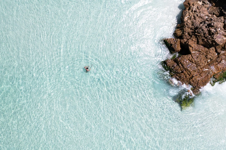 an aerial s of two people paddling their surfboards in the ocean