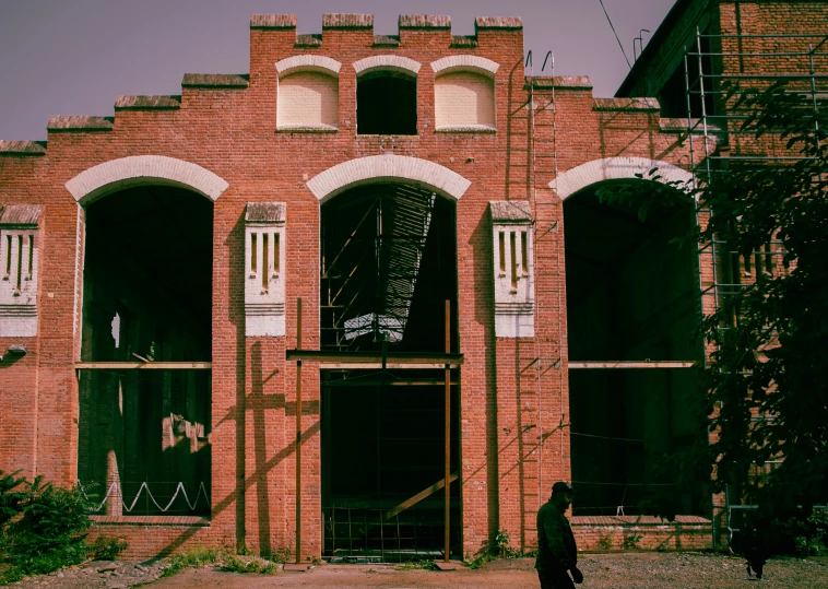 a woman is walking in front of an old red brick building