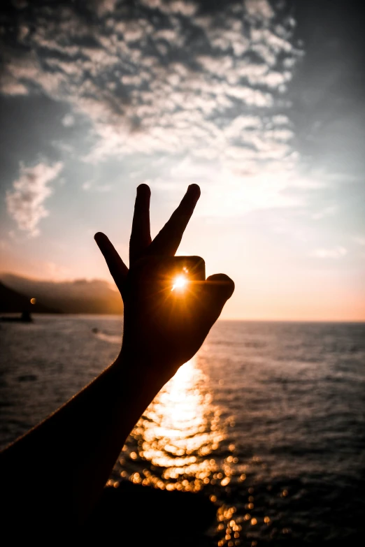 a person is holding their hand up towards the sun