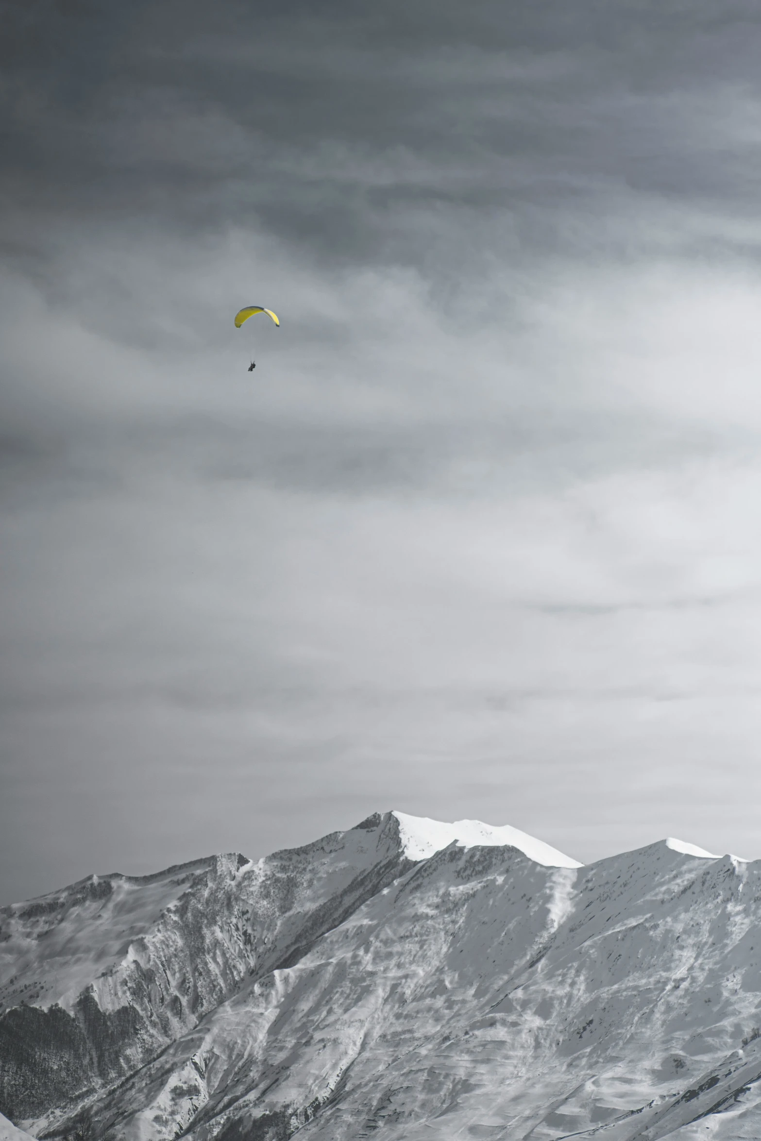 a para sailor flies near a snowy mountain range