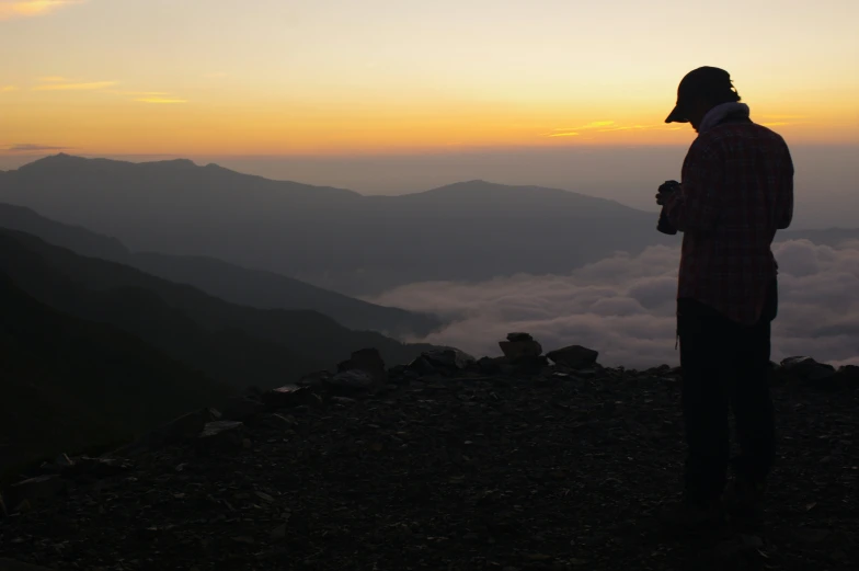 a person on top of a mountain looking at the clouds