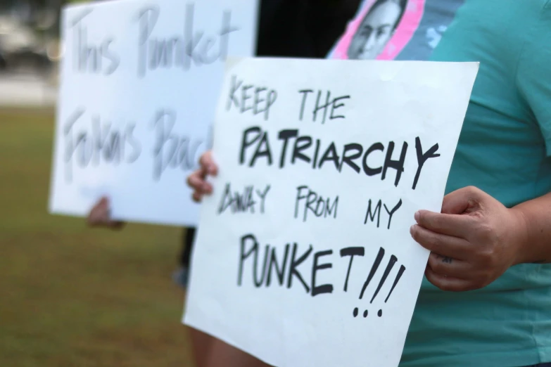 some people holding up signs outside with writing on them