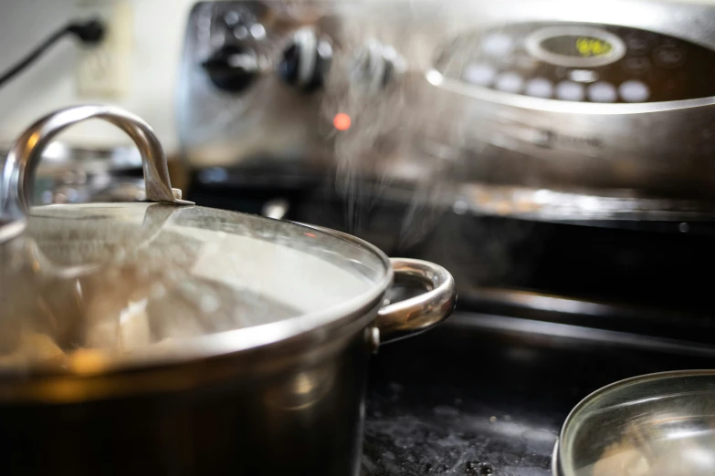 a stainless steel pot on a stove with the steam coming from it