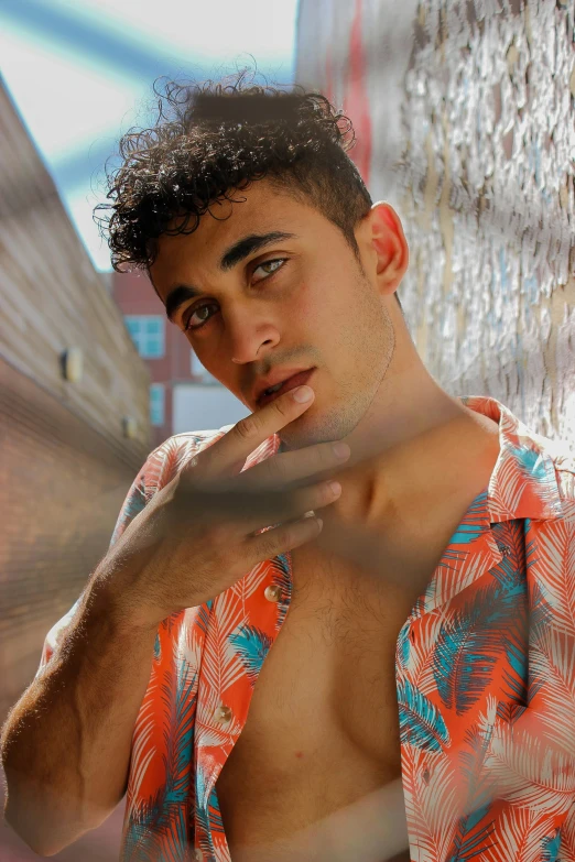 a young man poses near a wall and poses for a camera